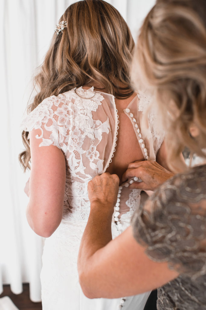 A simple and modern wedding at Triunfo Creek Vineyards, bride getting dressed with mom on wedding day