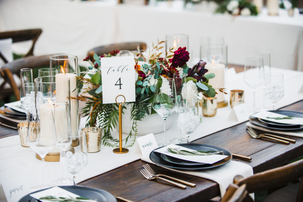 A simple and modern wedding reception at Triunfo Creek Vineyards, gold table number holders