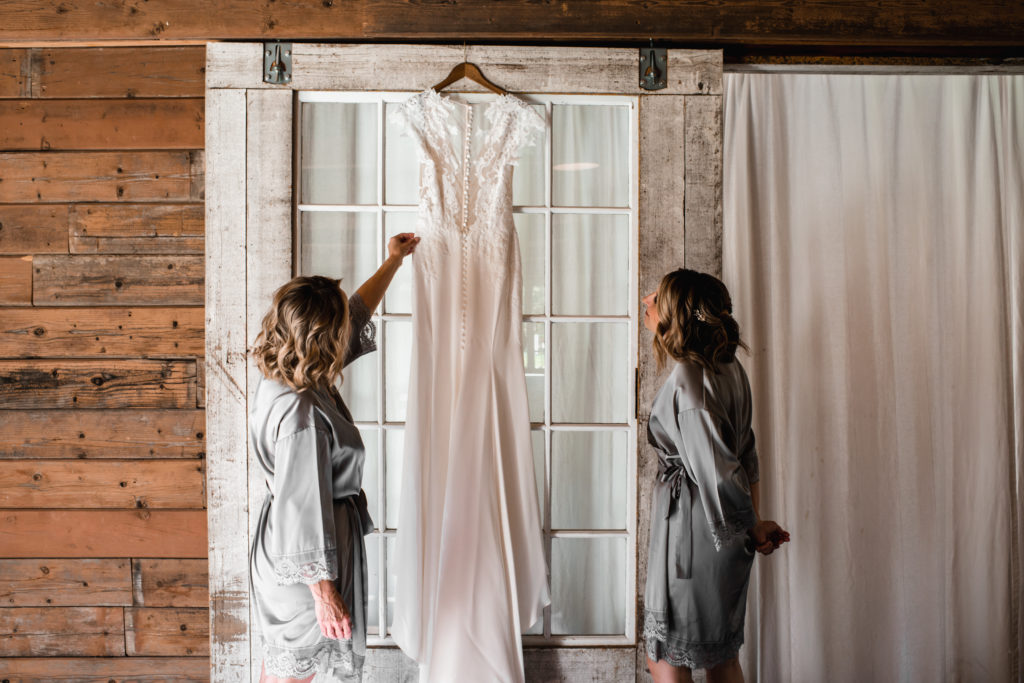 A simple and modern wedding at Triunfo Creek Vineyards, bridesmaids looking at lace wedding dress