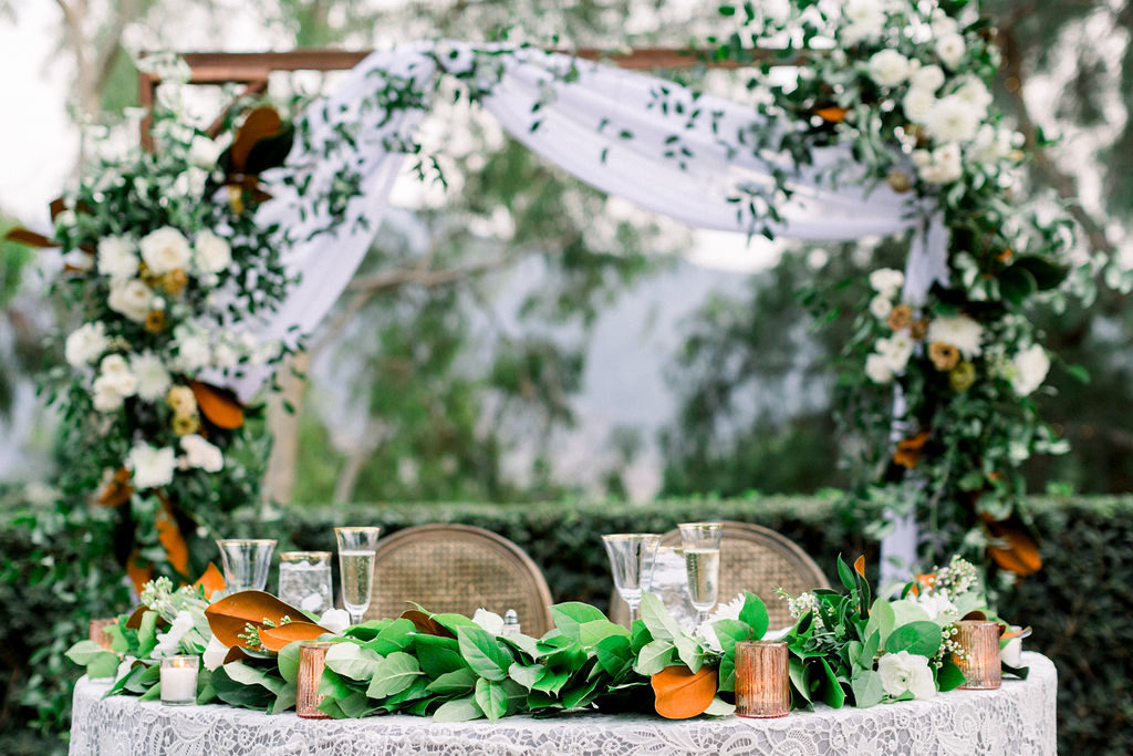 A Romantic Fall Wedding reception at Maravilla Gardens, sweetheart table with arch and magnolia leaf garland