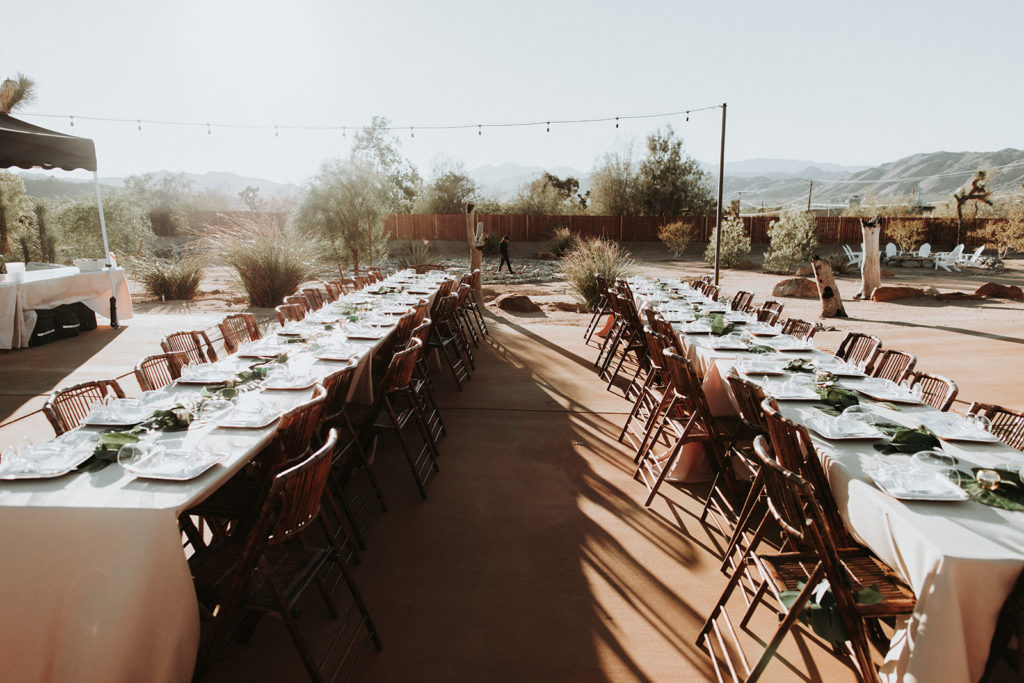 A Joshua Tree wedding reception at Tumbleweed Sanctuary, long farm tables with monstera leaf centerpieces