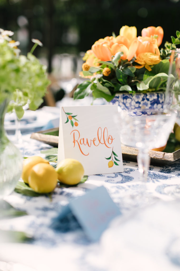An Al Fresco Wedding reception at the Valley Hunt club, Italian inspired wedding reception, family style table with blue floral patterned tablecloth and fresh citrus, Italian city inspired table names