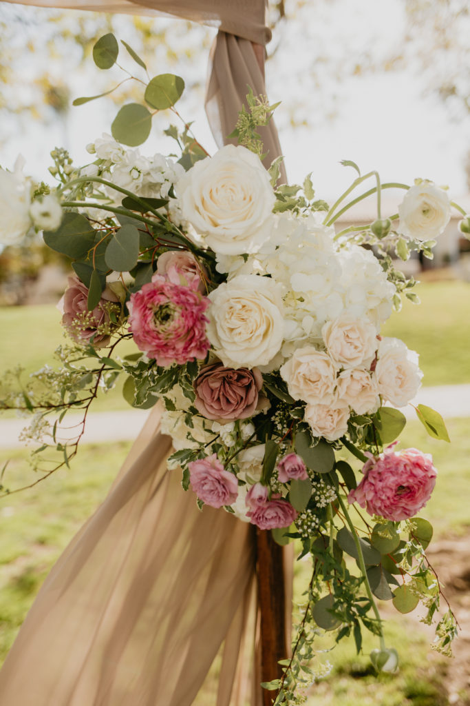 A music festival themed wedding ceremony at The Inn at Rancho Santa Fe, white and pink arch flowers