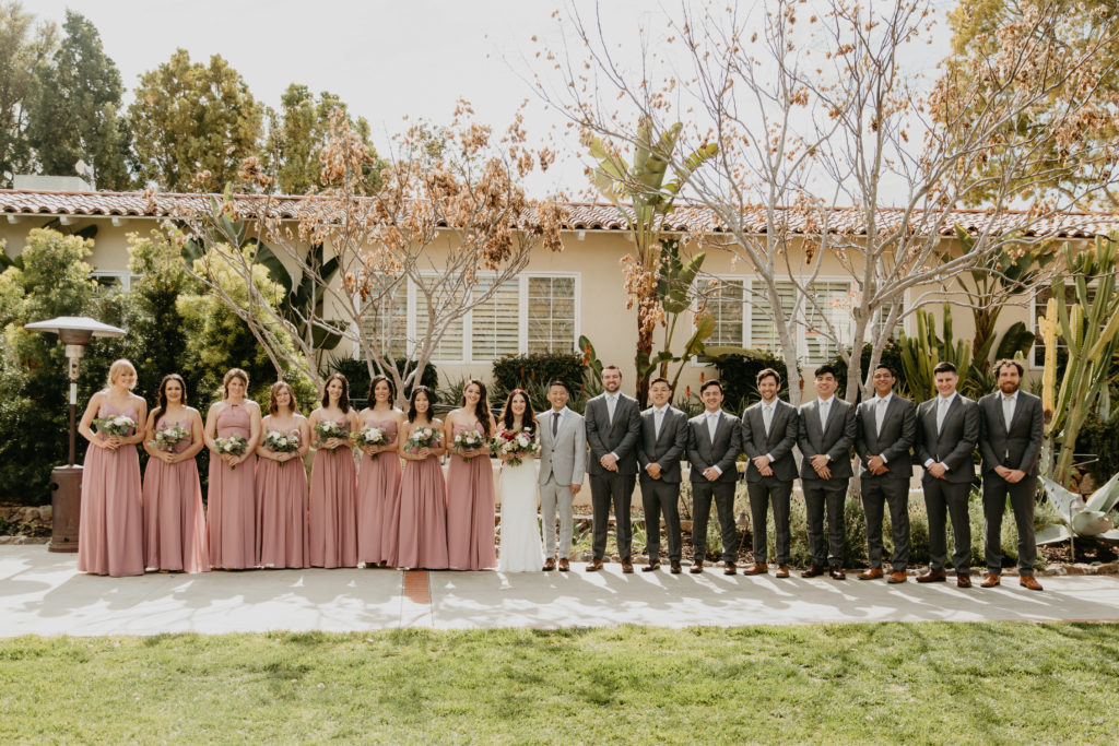 A music festival themed wedding at The Inn at Rancho Santa Fe, wedding party portrait shots, bridesmaids in blush bridesmaid dresses, groomsmen in dark grey suits