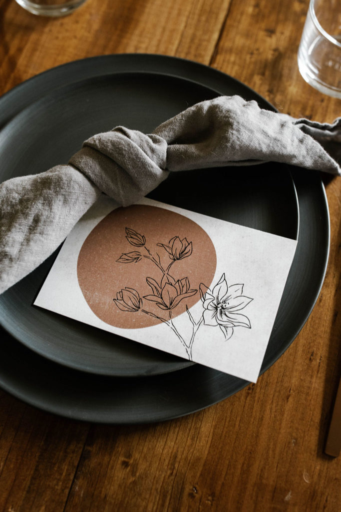 Create Dinners tables cape with black matte plates and muted burgundy menu card