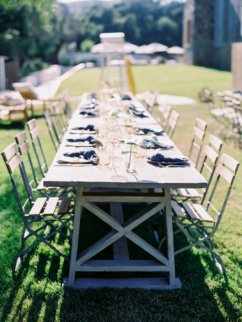 A California-cool rehearsal dinner at Calamigos Ranch, natural farm table with blue napkins and drink ware