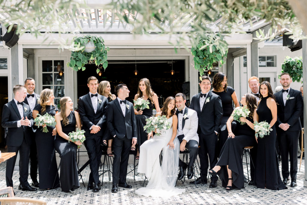 A classic greenhouse wedding at Dos Pueblos Orchid Farm, bride and groom with wedding party in black dresses and suits