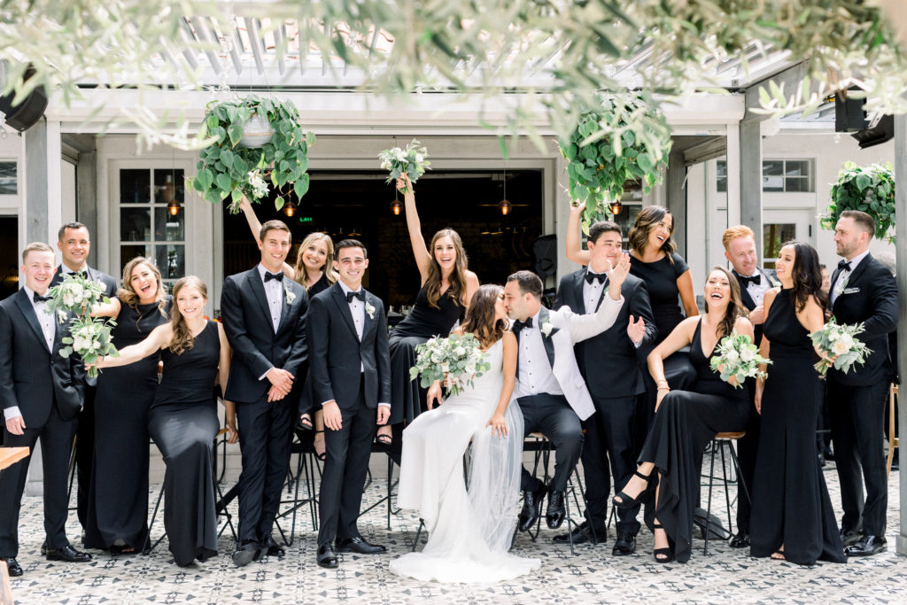 A classic greenhouse wedding at Dos Pueblos Orchid Farm, bride and groom with wedding party in black dresses and suits