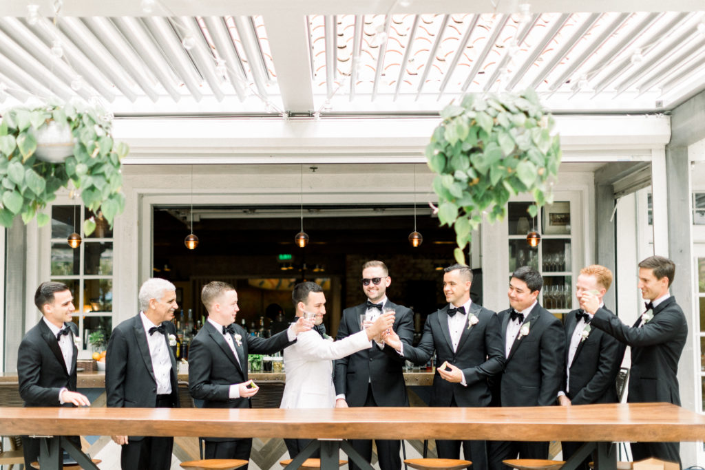 A classic greenhouse wedding at Dos Pueblos Orchid Farm, groom in white tux with groomsmen in black suits