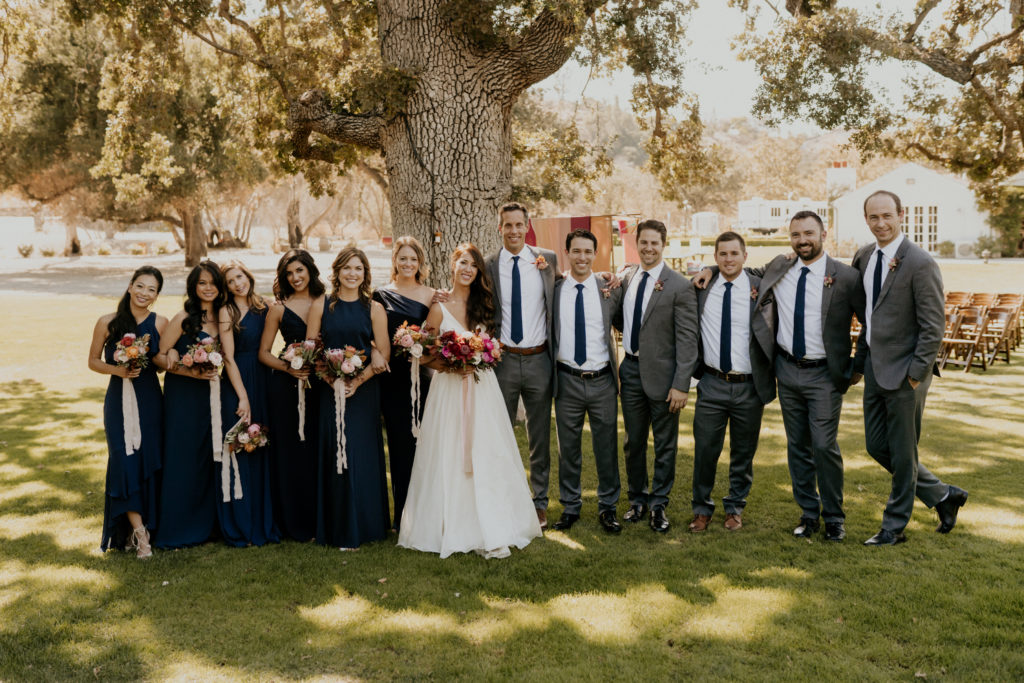 A whimsical wedding at Triunfo Creek Vineyards, bride and groom with wedding party in navy blue