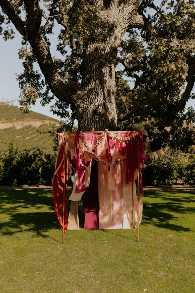 A whimsical wedding at Triunfo Creek Vineyards, bohemian arch with fabric and tassels 