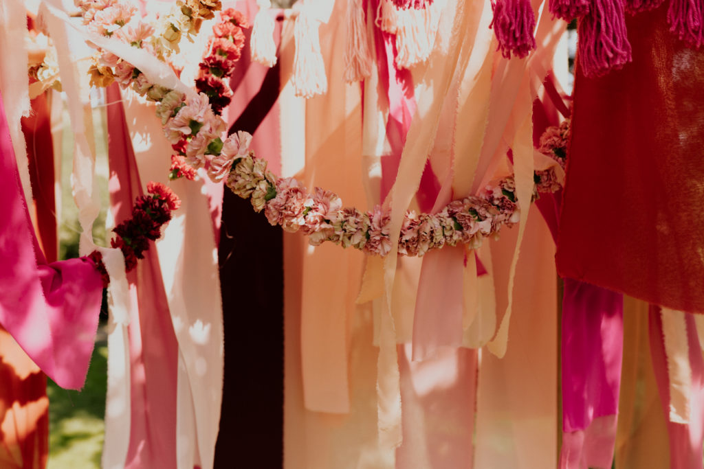 A whimsical wedding at Triunfo Creek Vineyards, bohemian arch with pink fabric and tassels