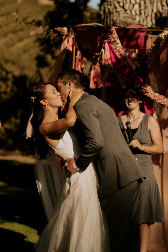 A whimsical wedding ceremony at Triunfo Creek Vineyards, bride and groom kiss
