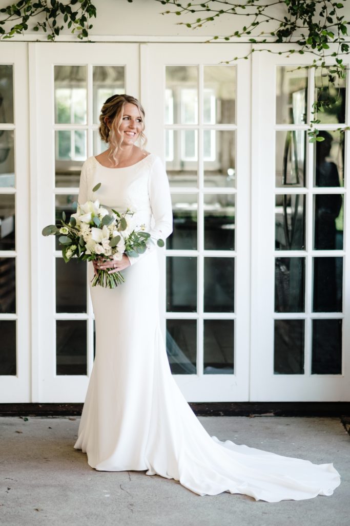 A Classic Vineyard Wedding at Triunfo Creek Vineyards, bride wearing long sleeve wedding dress with green and white bridal bouquet