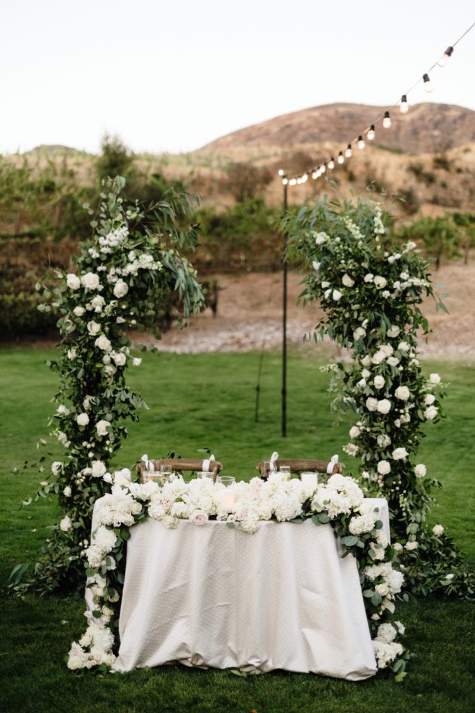A Classic Vineyard Wedding reception at Triunfo Creek Vineyards, sweetheart table with green and white flowers