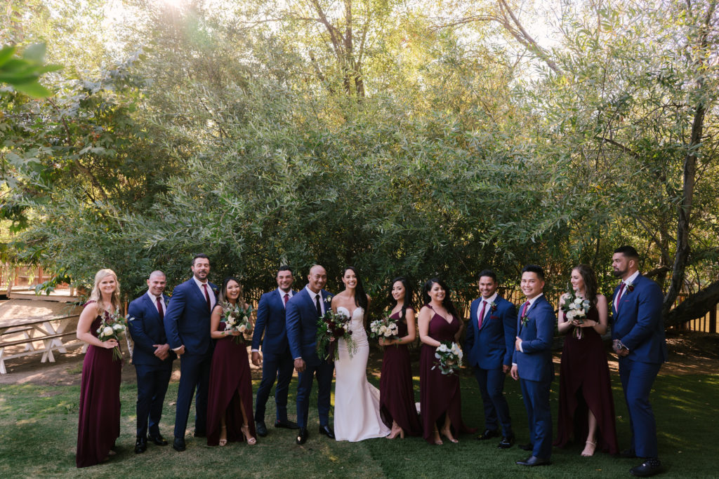 A Fall Wedding at Calamigos Ranch, bride and groom with wedding party, bridesmaids in dark burgundy dresses and groomsmen in dark blue suits