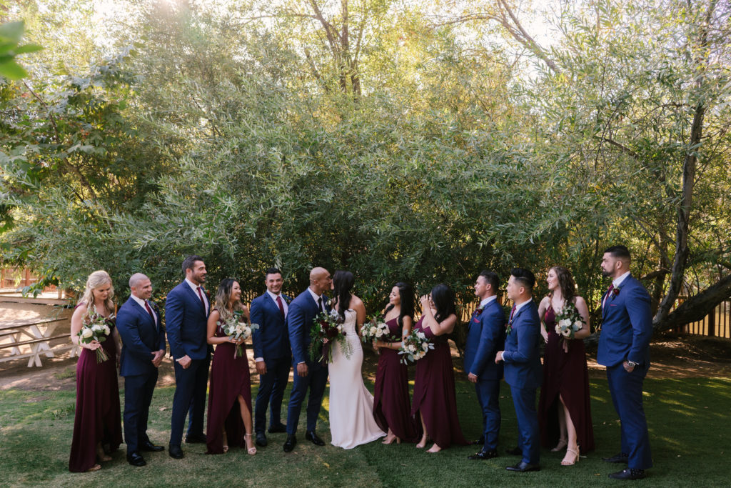 A Fall Wedding at Calamigos Ranch, bride and groom with wedding party, bridesmaids in dark burgundy dresses and groomsmen in dark blue suits