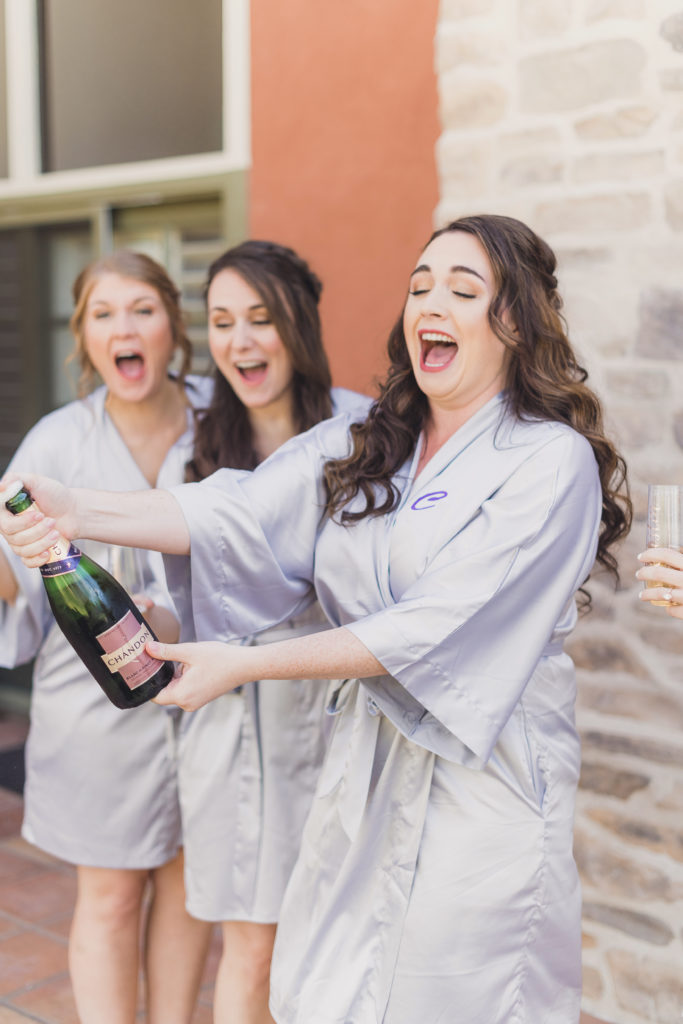 A Springtime Malibu Wedding at Calamigos Ranch, bride and bridesmaids pop champagne