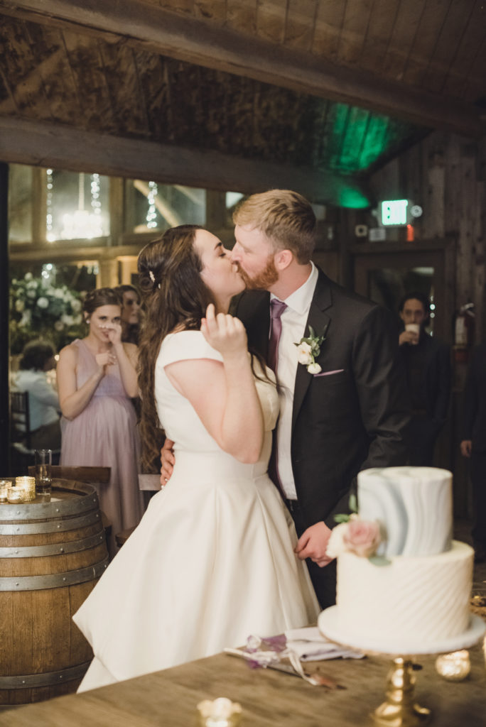 A Springtime Malibu Wedding reception at Calamigos Ranch, bride and groom kiss after cutting cake