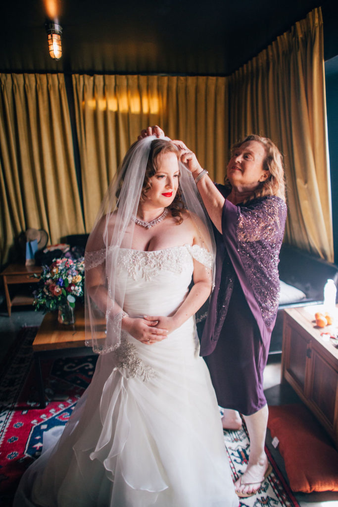 bride getting veil put on by mom