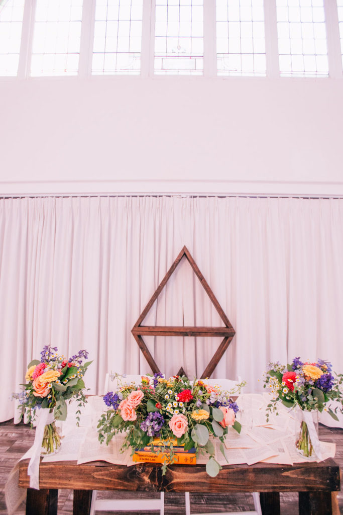 Storybook themed wedding reception at The York Manor with geometric sweetheart table backdrop and bright colorful floral centerpieces