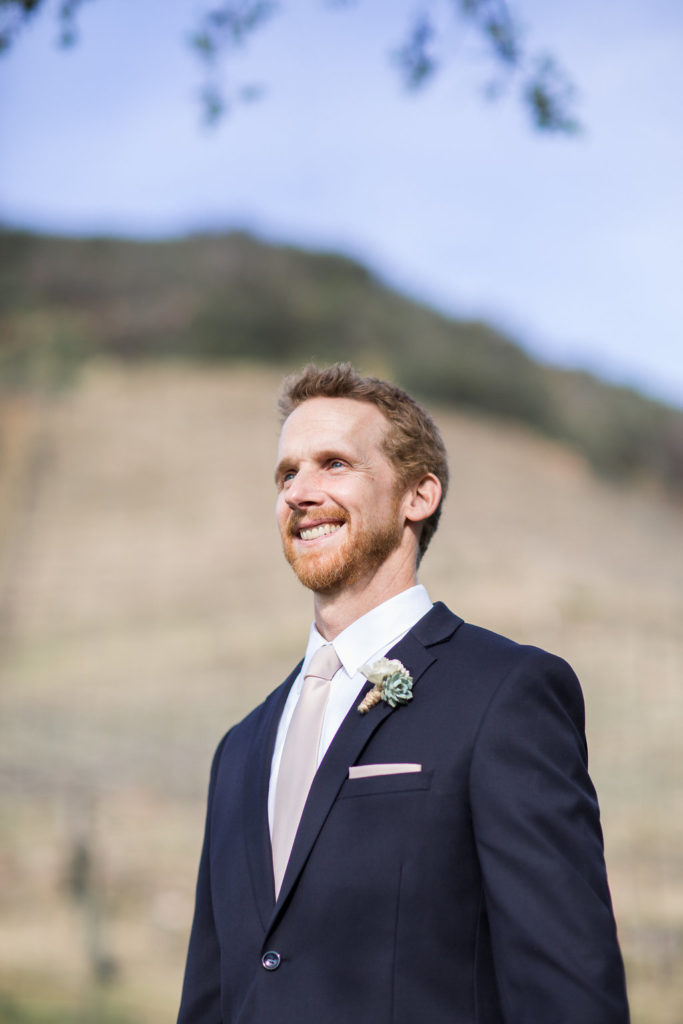 groom during ceremony wearing black suit and pink tie