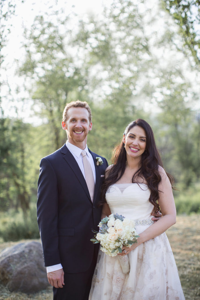 bride in strapless wedding dress with brocade details and groom with black suit and pink tie first look in vineyard