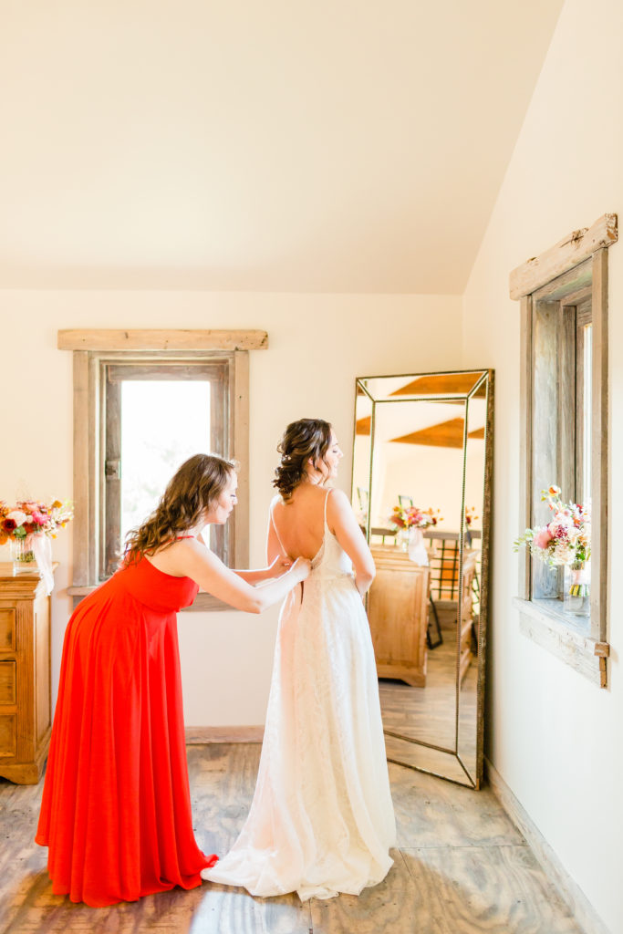 bride getting ready for wedding with bridesmaid