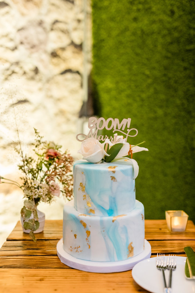 boom married wedding cake topper on blue and gold marbled cake