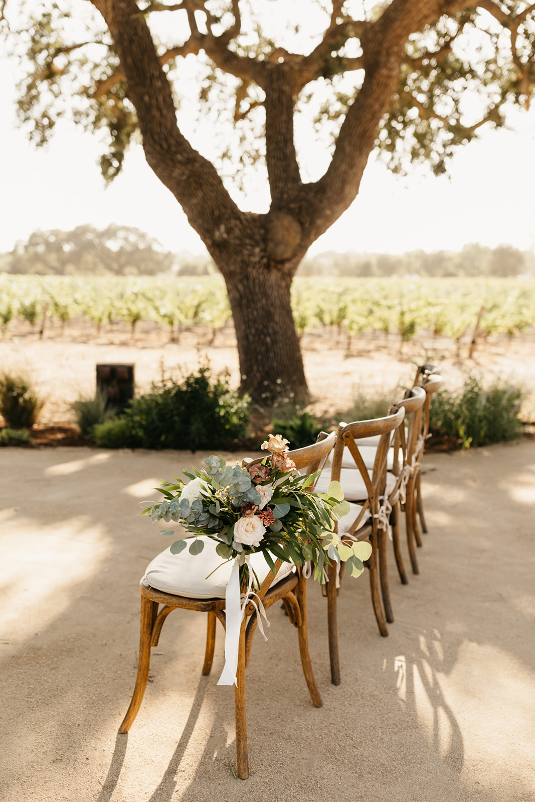 cross back ceremony chair with large floral arrangement tied to the side