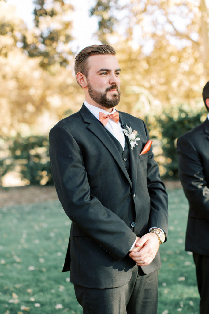 minimalist autumn wedding ceremony. groom with black suit and rust colored tie