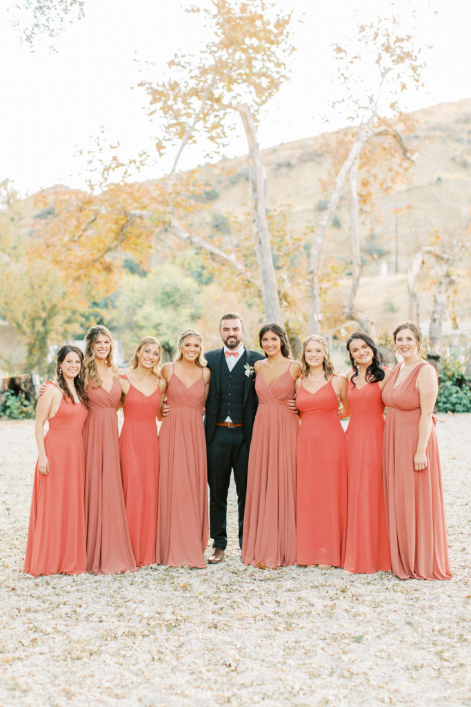 groom with bridesmaids in rust colored dresses portrait shot