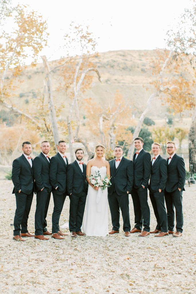 bride with groomsmen in black suit and rust colored ties portrait shot