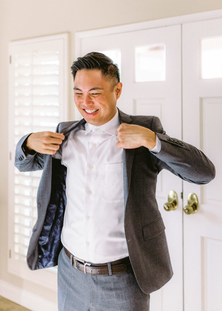 groom getting ready for small backyard ceremony wearing a grey suit