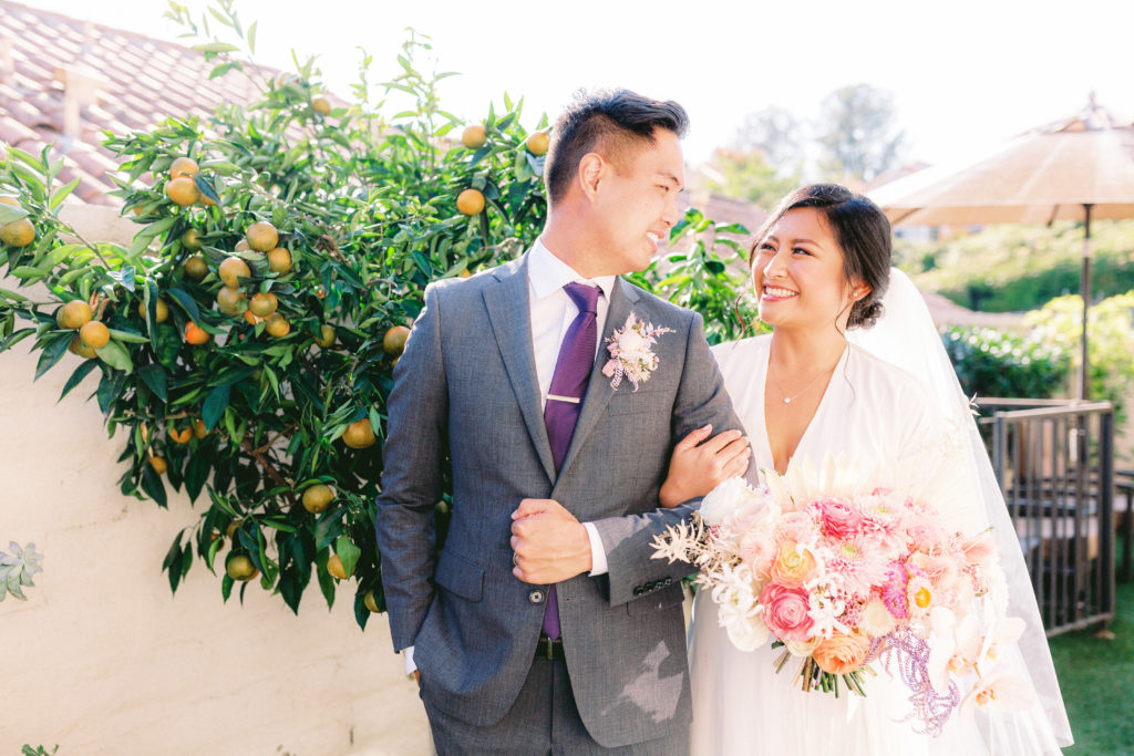 bride wearing Reformation wedding dress and groom with grey suit and purple tie portrait shot after their backyard ceremony