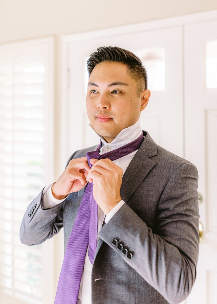groom getting ready for small backyard ceremony wearing a grey suit