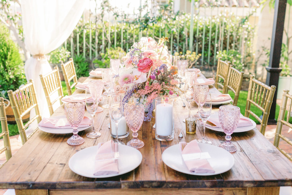 small backyard wedding reception with gold chivari chairs,  pink and purple floral centerpieces and acrylic place cards