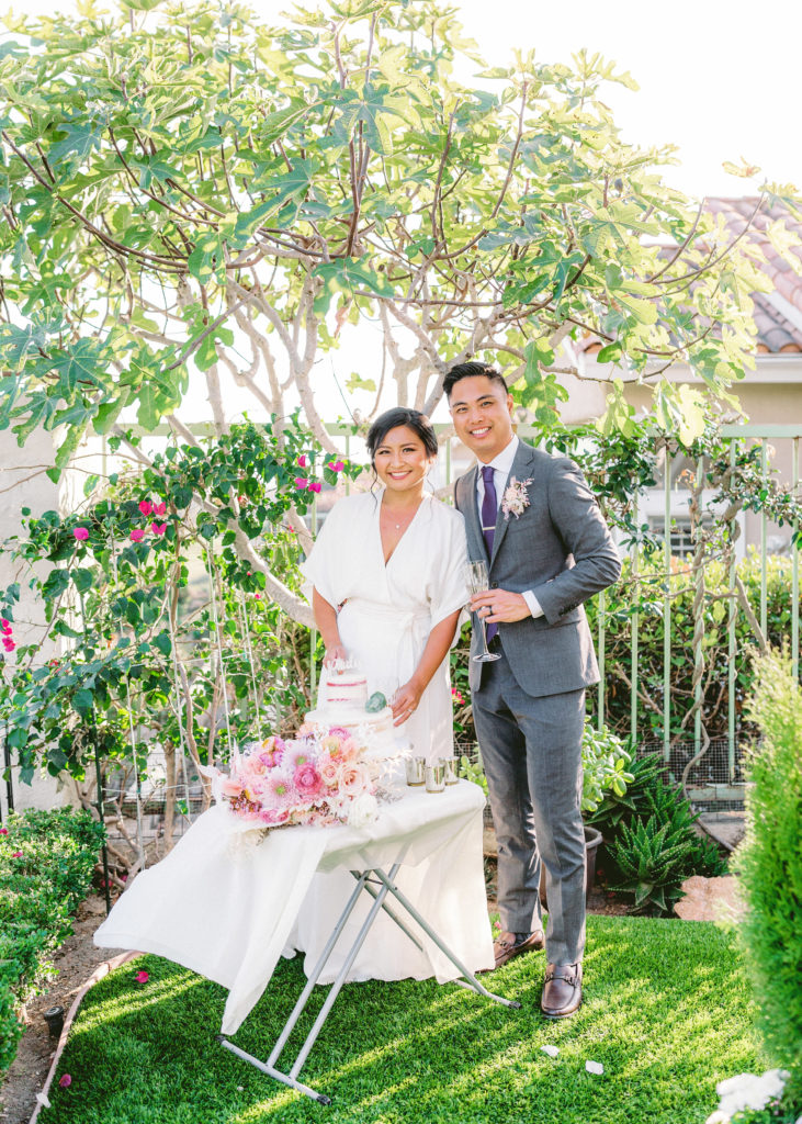 bride and groom cut wedding cake in backyard