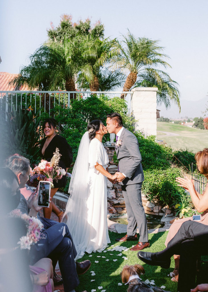 bride and groom first kiss during wedding in a backyard ceremony