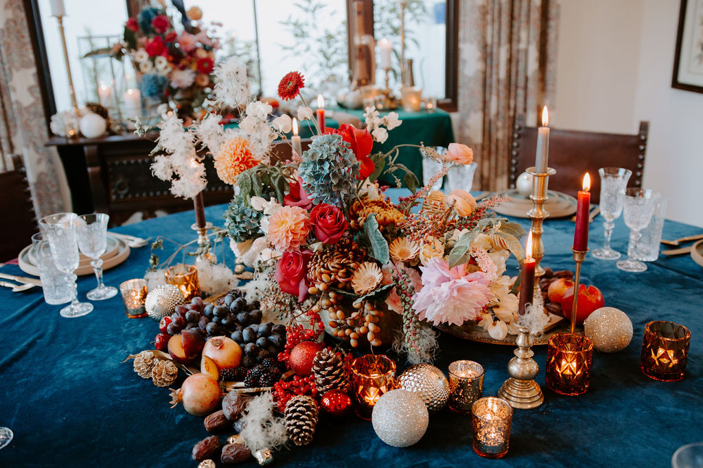 cozy non-traditional holiday decorations with a deep blue tablecloth and wild centerpiece with fruit