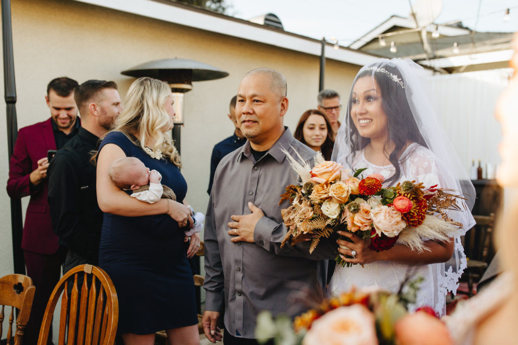 Bride walks down aisle with veil during backyard wedding