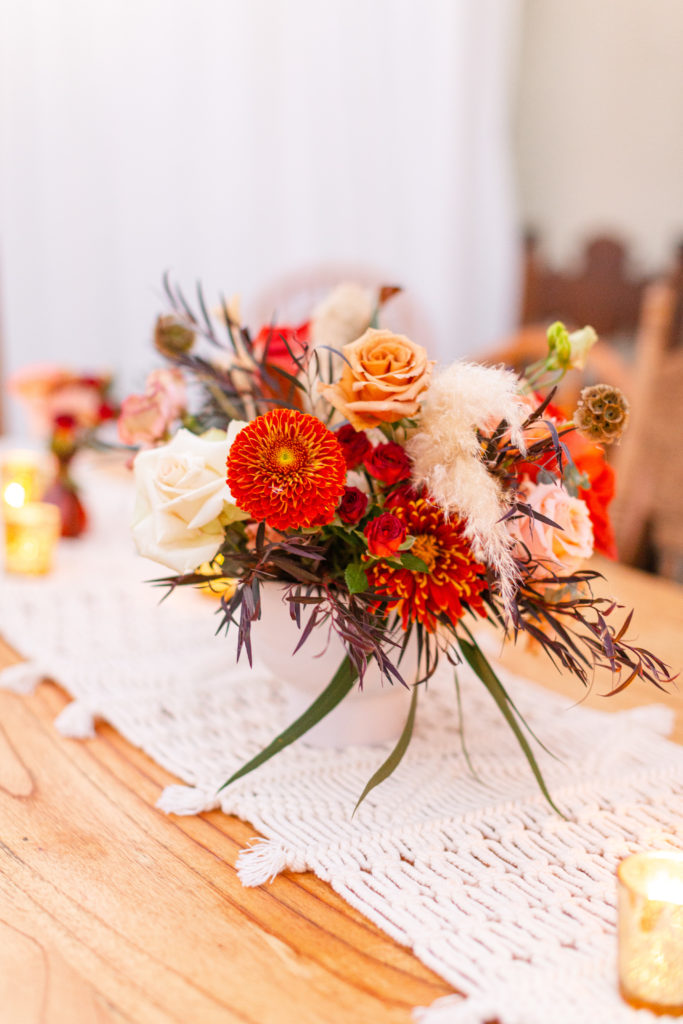 Bohemian style backyard wedding reception with red, orange and white florals 