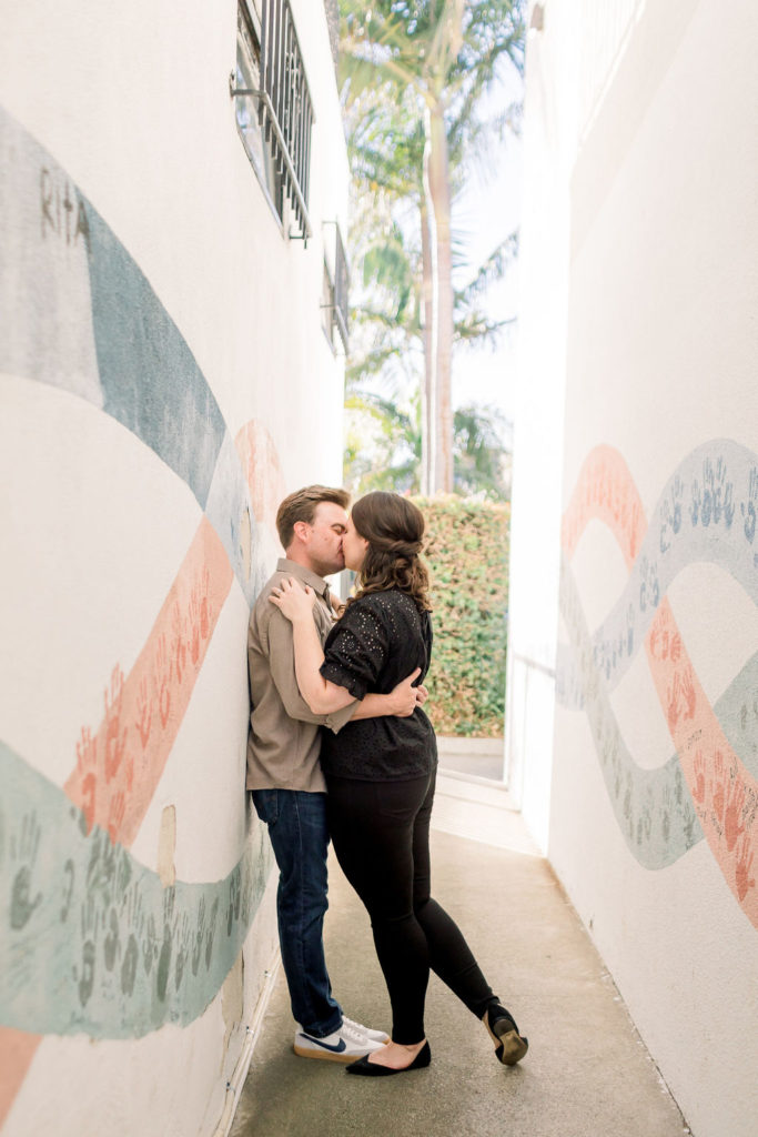 engagement photo session with couple kissing in front of a painted mural in Los Angeles