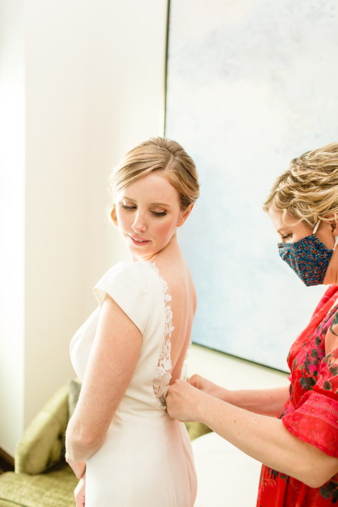 bride getting into wedding dress with help from sister