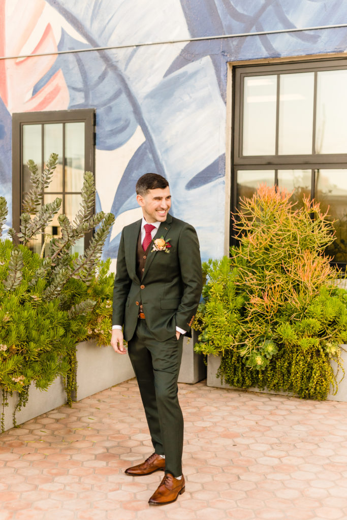 Groom wearing dark grey suit and red tie getting ready for his spring wedding at Hotel Figueroa