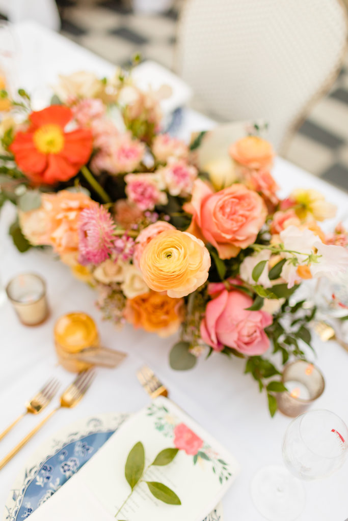 spring wedding reception at Ricks in Hotel Figueroa with pink and orange floral centerpieces and cafe inspired chairs and mix and matched vintage french plates and gold silverware