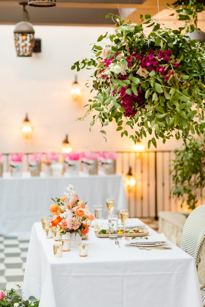spring wedding reception at Ricks in Hotel Figueroa with pink and orange floral centerpieces and cafe inspired chairs and mix and matched vintage french plates and gold silverware