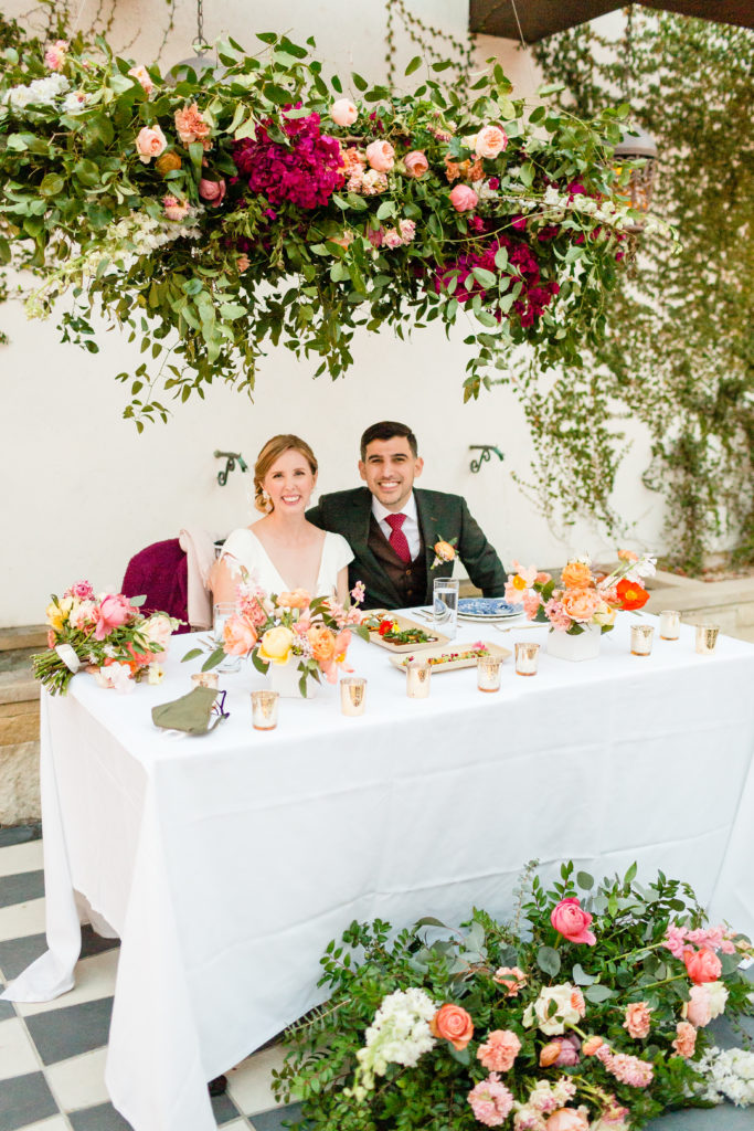 bride and groom at sweetheart table at Hotel Figueroa with flower installation overhead