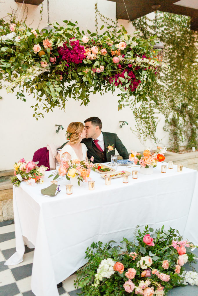 bride and groom kiss at sweetheart table at their spring wedding at Hotel Figueroa