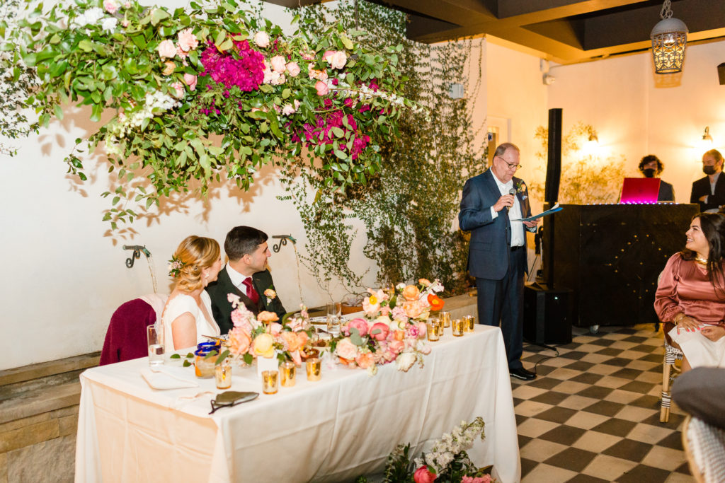 bride and groom sit at sweetheart table during father of the bride toasts